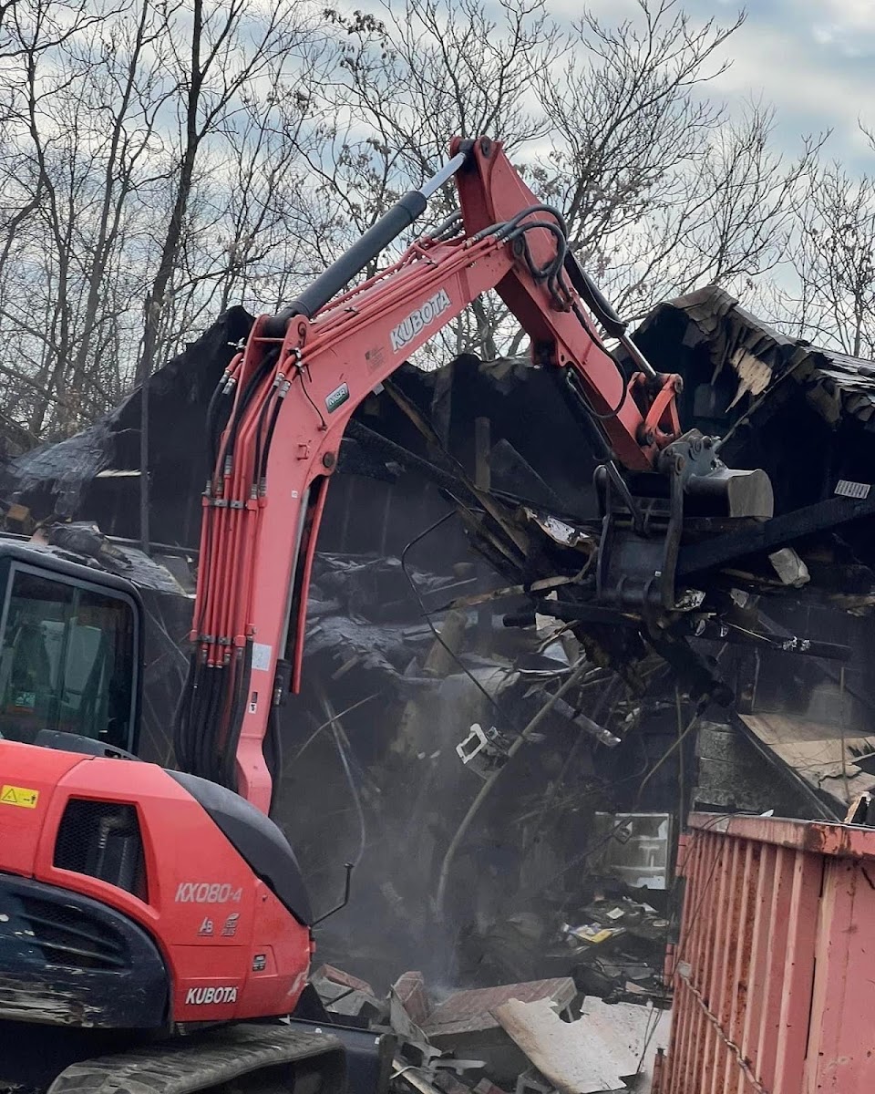An excavator tearing into the remains of a collapsed structure